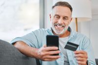 Foto: Mann mit Smartphone und Kredikarte